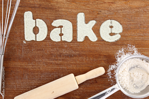 Stencil word "bake" made with flour on wooden table