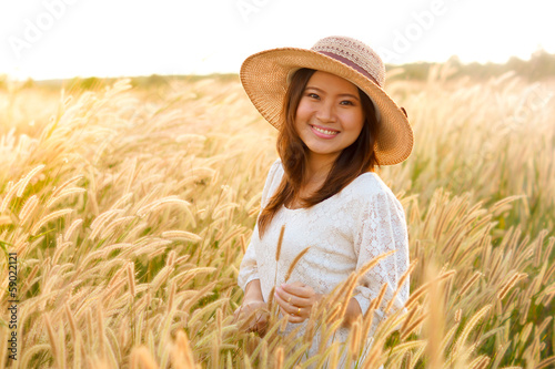 young Asian girl standing in the middle of a golden grass field