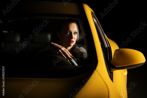 Fashionable young woman driving a car in the night