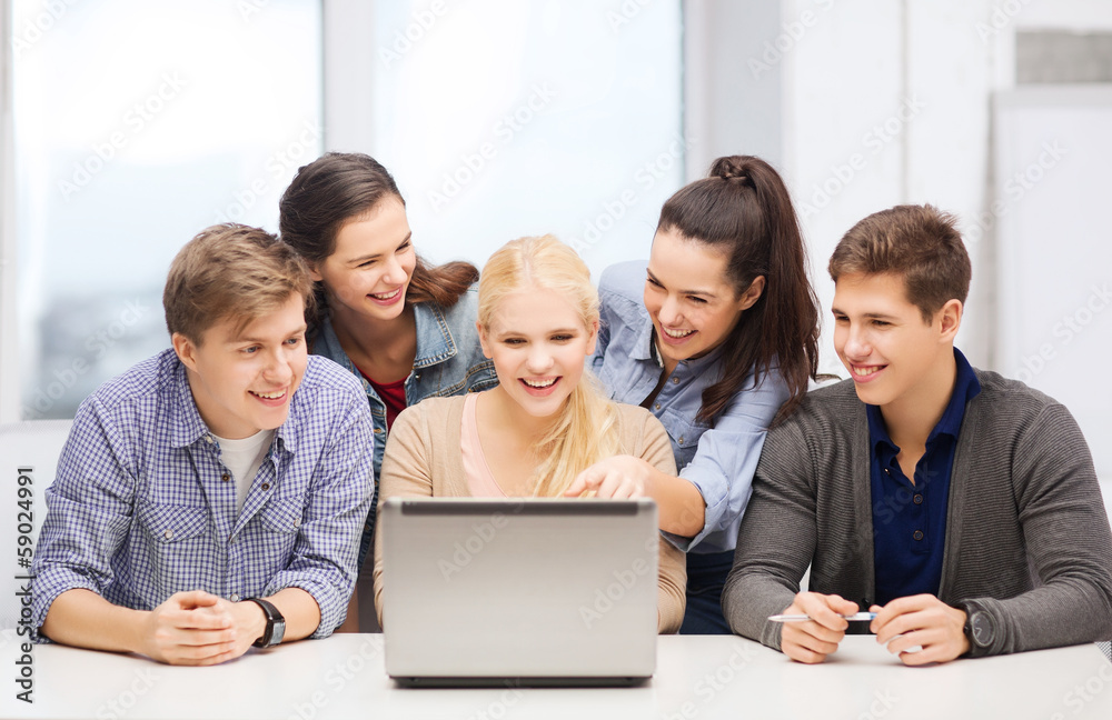smiling students looking at laptop at school