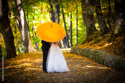 Young married couple in love kissing under umbrella photo