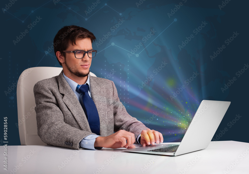 Handsome man sitting at desk and typing on laptop with abstract Handsome man sitting at desk and typing on laptop with abstract