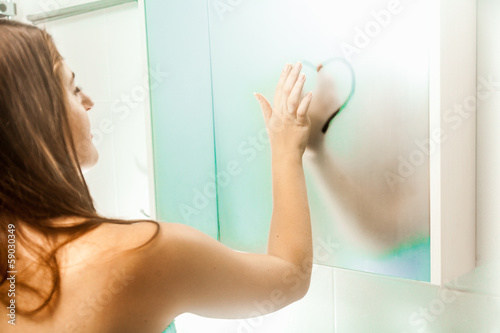 Canvas Print nude woman drawing heart on steamy mirror at bathroom