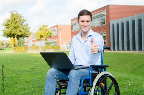 Rollstuhlfahrer mit Notebook zeigt Daumen © Racle Fotodesign