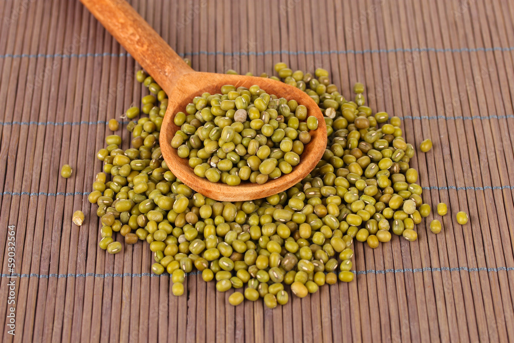 Mung beans over wooden spoon on color background Mung beans over wooden spoon on color background