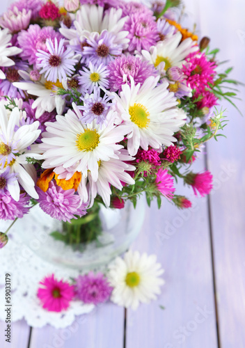 Wildflowers in glass vase on napkin on wooden table