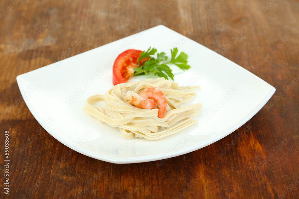 Pasta with shrimps on white plate, on wooden background Pasta with shrimps on white plate, on wooden background