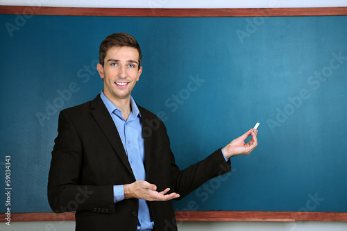 Young teacher near chalkboa...