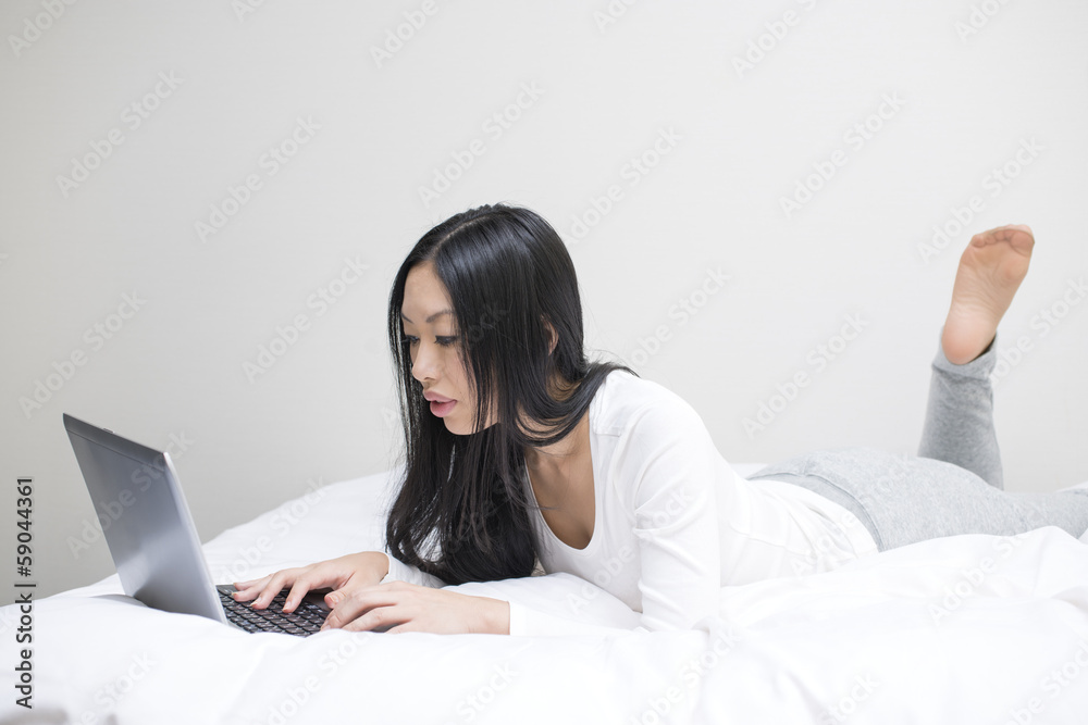うつぶせでノートパソコンを操作する女性 うつぶせでノートパソコンを操作する女性