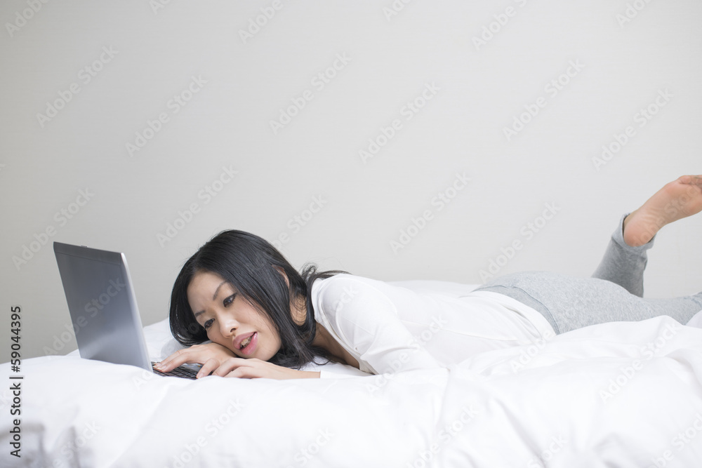 うつぶせでノートパソコンを操作する女性 Stock Photo Adobe Stock