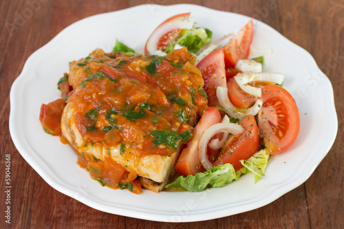 chicken with sauce and salad on plate