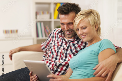 Embracing couple using digital tablet