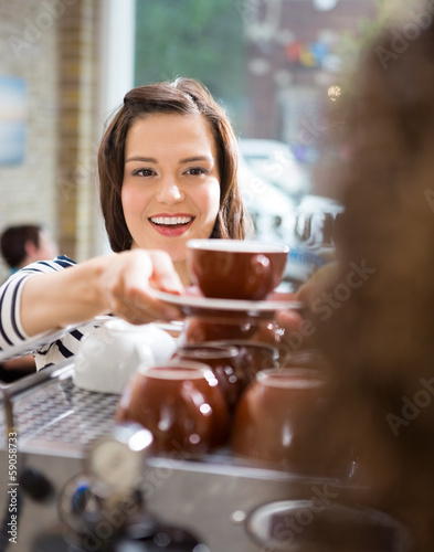 Customer Taking Coffee From Waitress In Cafe photo