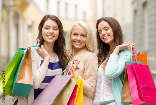 three smiling girls with shopping bags in ctiy