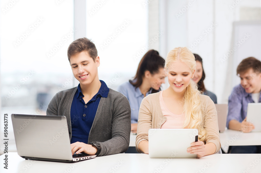 two smiling students with laptop and tablet pc two smiling students with laptop and tablet pc