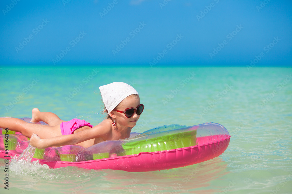 Little cute girl on pink air-bed in warm sea