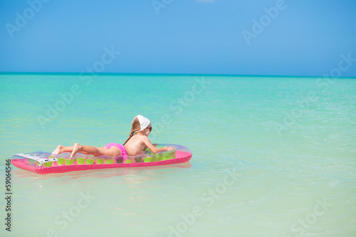 Little cute girl relax on pink air-bed in warm sea