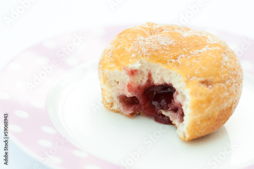 Jam doughnut with a mouthful taken out and jam showing