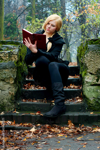 Beautiful girl reading a book on the stairs