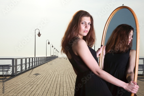 thoughtful woman looks at the reflection in mirror