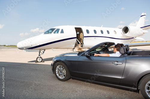 Pilot In Convertible Parked Against Private Jet © Tyler Olson