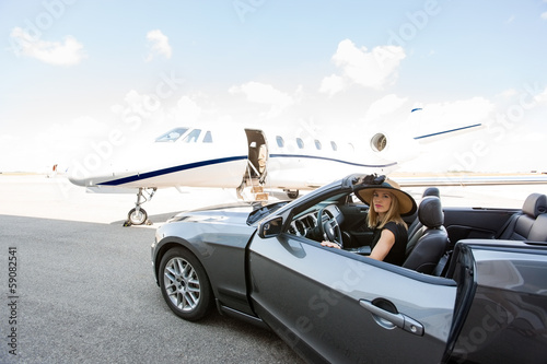 Woman Disembarking Car With Private Jet In Background photo