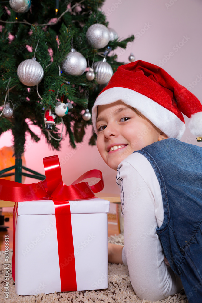 Happy little girl smiling with gift box near the Christmas tree. Happy little girl smiling with gift box near the Christmas tree.
