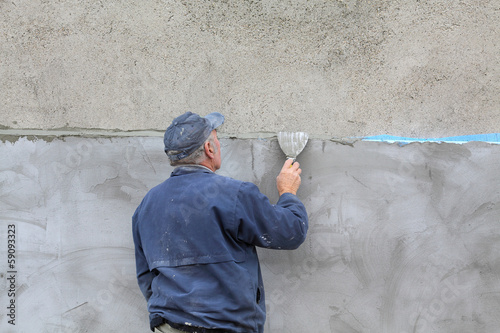 Worker spreading mortar over styrofoam insulation with trowel © sima
