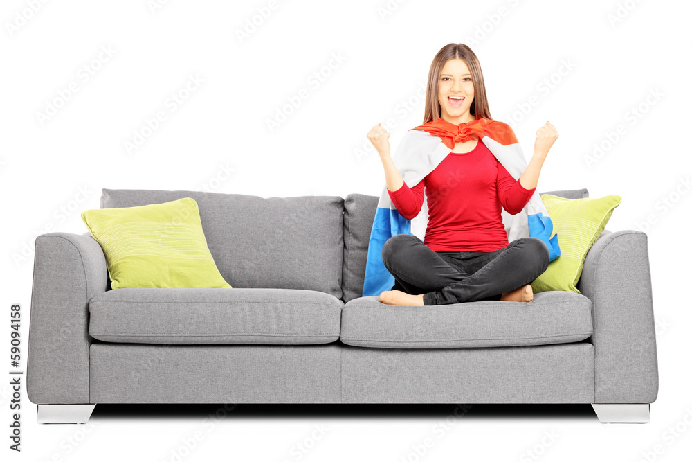 Young female sport supporter sitting on a modern sofa and cheeri