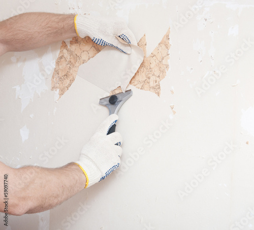 Hand removing wallpaper from wall photo