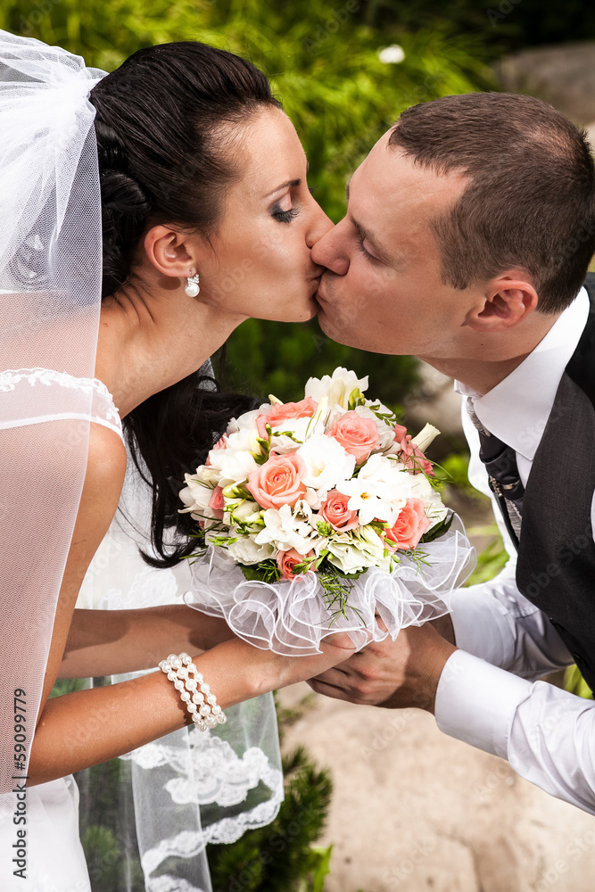 couple kissing passionately and holding wedding bouquet couple kissing passionately and holding wedding bouquet