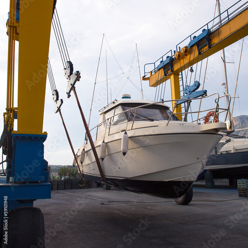 Boat wheel crane elevating motorboat to yearly paint photo