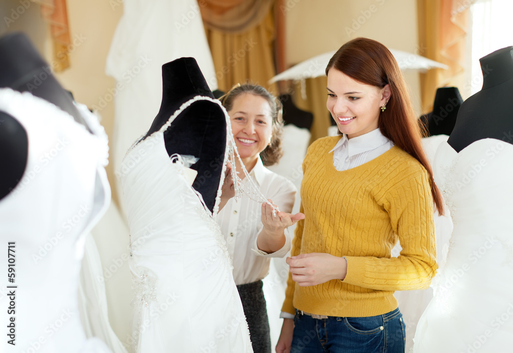 Obraz premium pretty bride chooses bridal outfit at wedding store