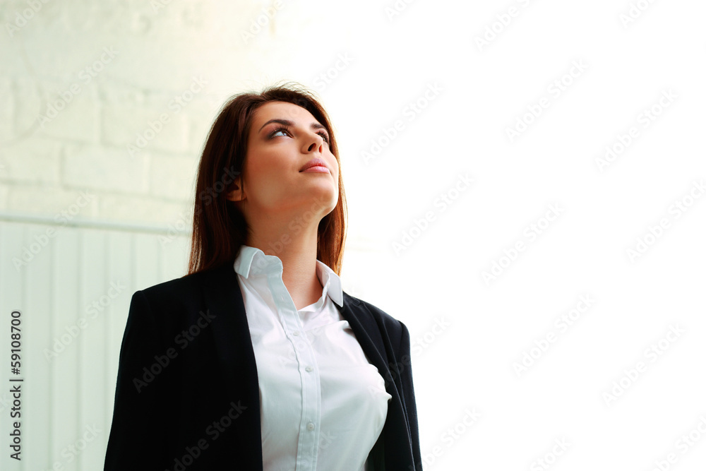 Young businesswoman looking up at copyspace in office Young businesswoman looking up at copyspace in office