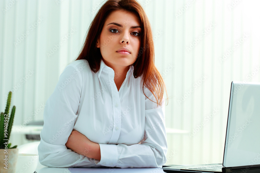 Young thoughtful businesswoman sitting at the table in office Young thoughtful businesswoman sitting at the table in office