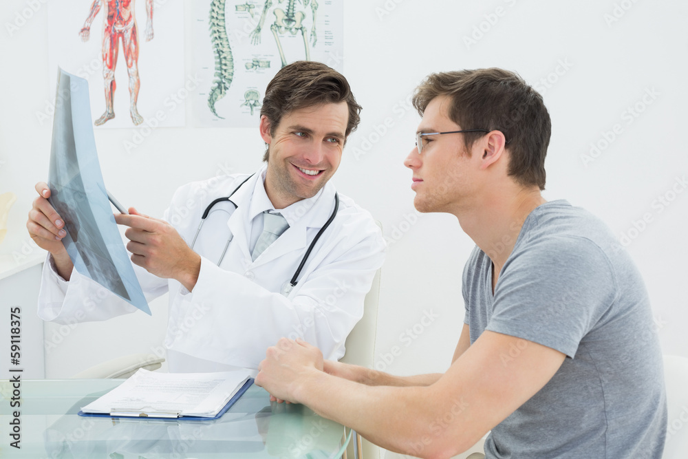 Fototapeta premium Smiling male doctor explaining spine x-ray to patient