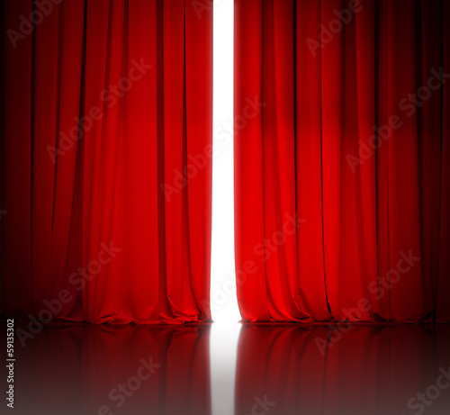 red theater or cinema curtain slightly open and white light behi