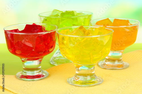 Tasty jelly cubes in bowls on table on light background