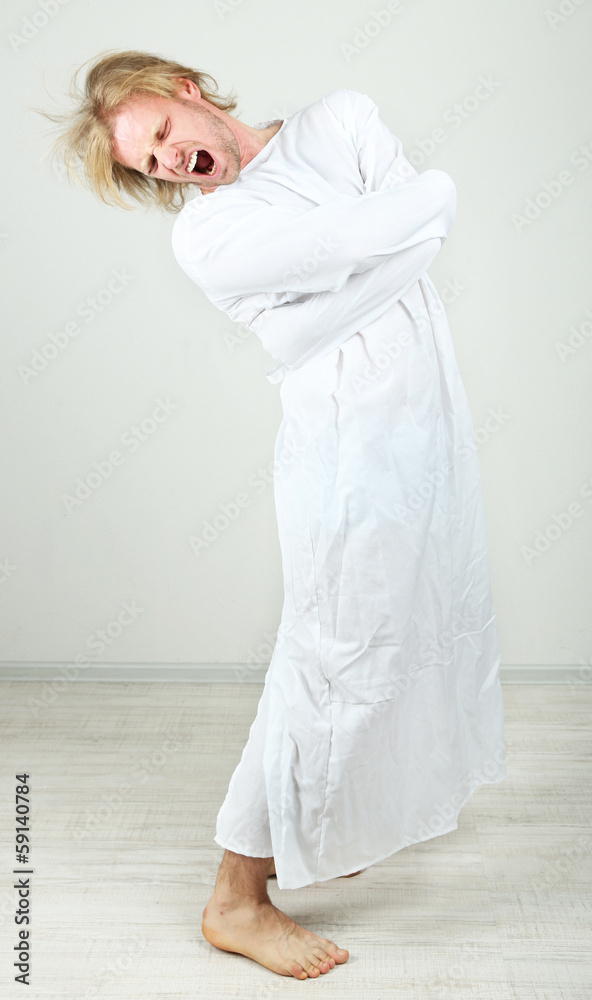 Mentally ill man in strait-jacket on gray background Mentally ill man in strait-jacket on gray background