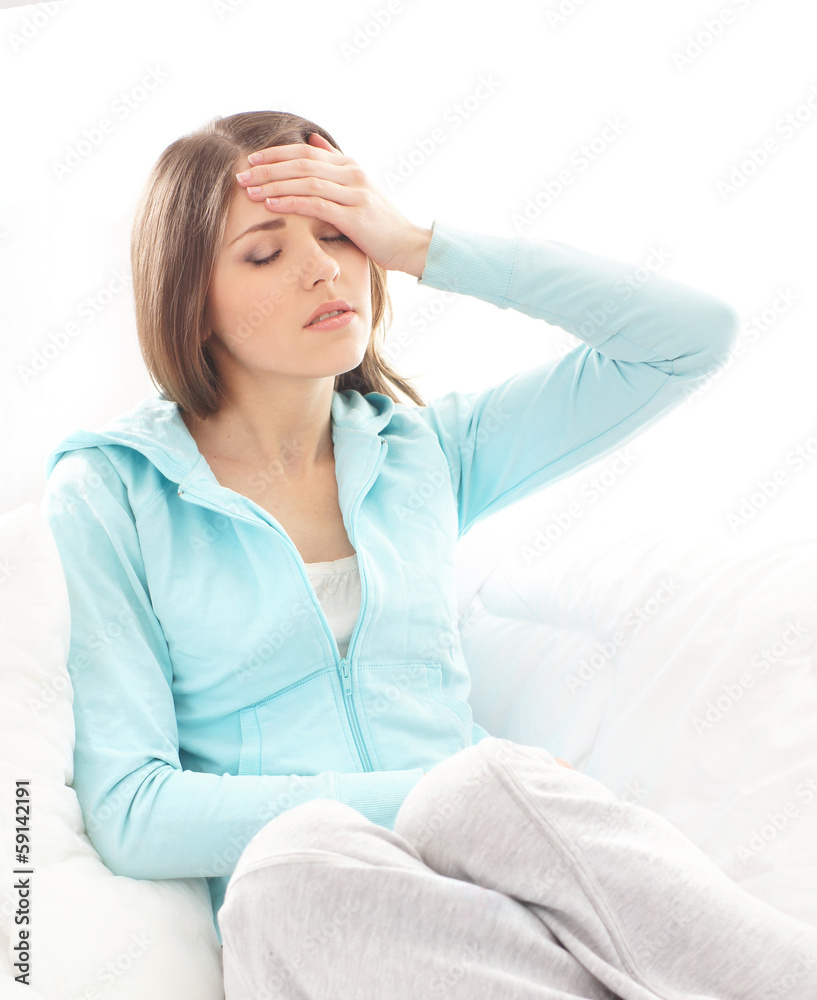 A young woman suffering from the pain in the head on white A young woman suffering from the pain in the head on white