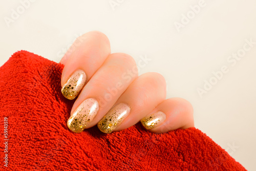 hand with gold nails holding a red towel