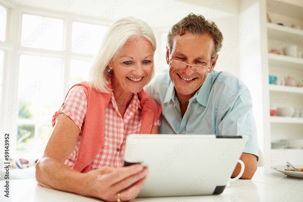 Smiling Middle Aged Couple Looking At Digital Tablet Smiling Middle Aged Couple Looking At Digital Tablet