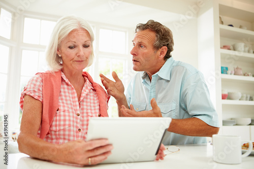 Worried Middle Aged Couple Looking At Digital Tablet