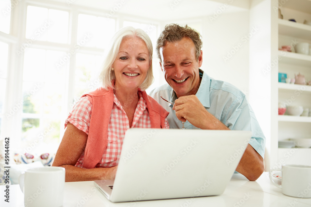 Smiling Middle Aged Couple Looking At Laptop