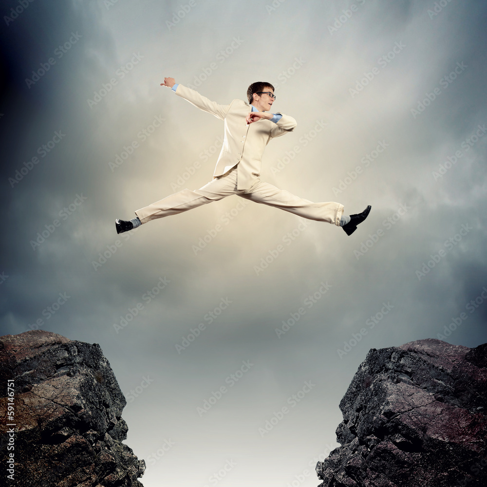 Businessman jumping over gap