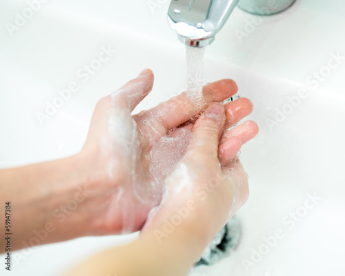Close-up of kid hands under stream of water from faucet