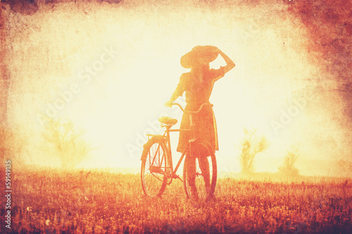 Girl on a bike in the countryside in sunrise time. © Masson