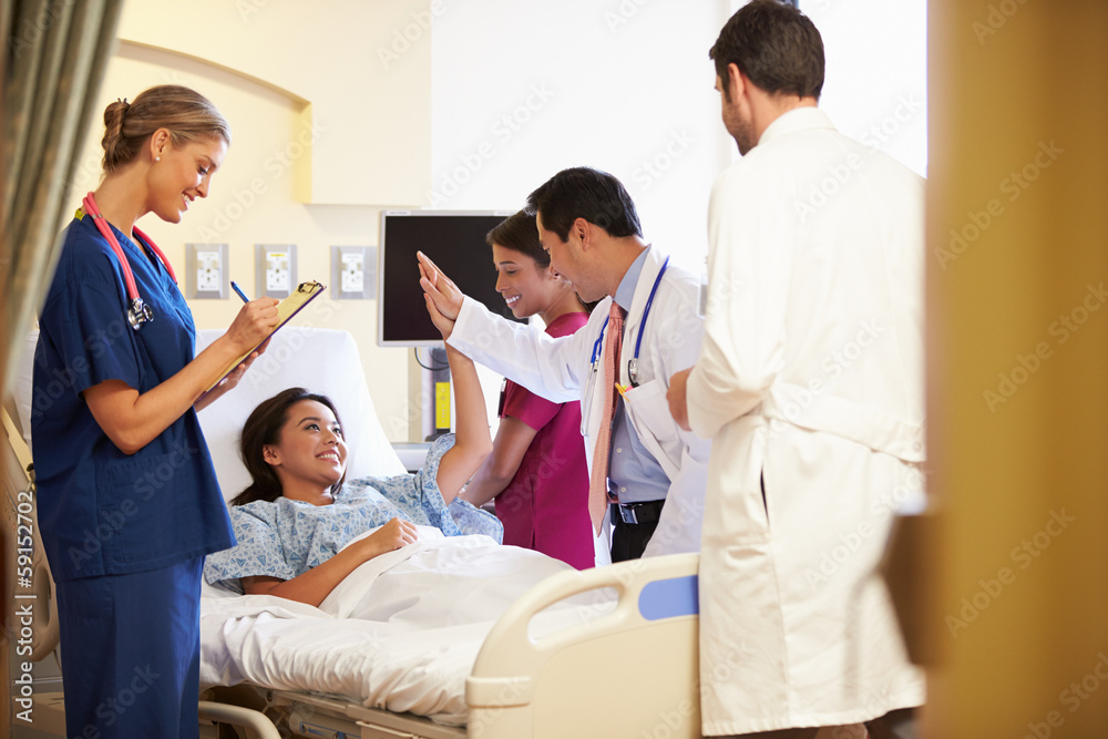 Medical Team Meeting Around Female Patient In Hospital Room Medical Team Meeting Around Female Patient In Hospital Room