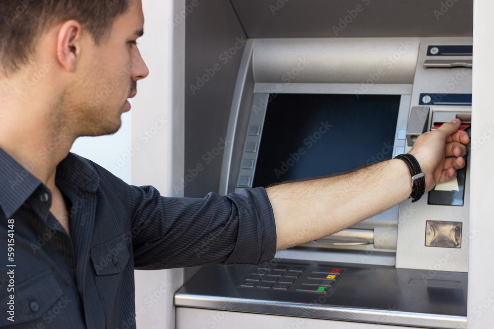 Young man withdrawing money from an ATM Young man withdrawing money from an ATM