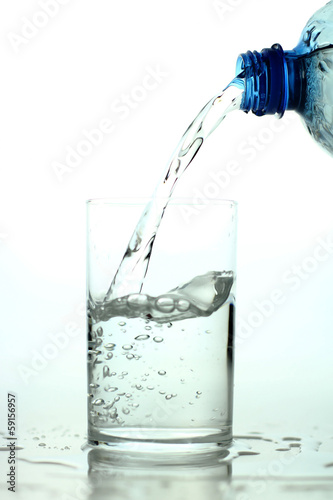 Pouring water on a glass on white background